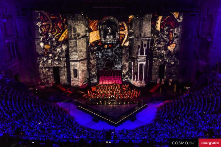 Photo prise depuis les gradins, on aperçoit les musiciens et le public. Sur la façade du théâtre sont projetées des illustrations de Philippe Druillet